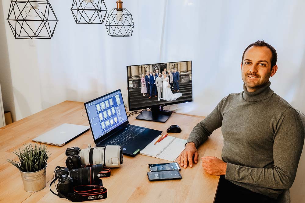 Fotograf Martin Bräutigam sitzt freudig am Schreibtisch